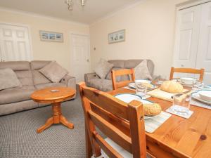 una sala de estar con una mesa y un sofá en Seagulls Nest, en Bridport