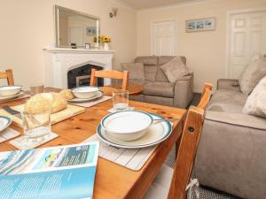 una sala de estar con una mesa de madera con platos. en Seagulls Nest, en Bridport