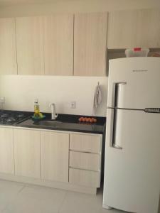 cocina blanca con nevera y fregadero en Casa perto da Praia do Laranjal, en Pelotas 2 fotos más