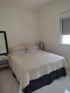 Una habitación blanca con una cama y una ventana en Casa perto da Praia do Laranjal, en Pelotas