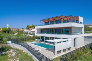 ein großes Haus mit einem davorliegenden Swimmingpool in der Unterkunft Villa Eligo mit 2 Whirlpools, Meerblick, Pool und Fitnessraum in Premantura