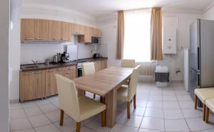 a kitchen with a wooden table and white chairs at Csömöri Vendégház in Csömör