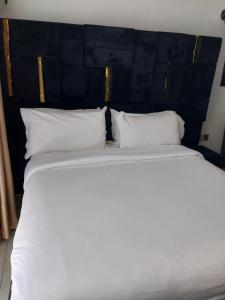 内罗毕Hellen's Condo的一张铺着白色床单和枕头的大床