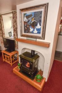 einen Kamin mit einem Herd im Wohnzimmer in der Unterkunft Last-Minute Escapes l Sleeps Up to 4 l A delightful thatched cottage with all the modern facilities you will require l There are 2 bedrooms, one with a double bed l the other with two singles l Carrick Thatched Cottage l WeStayBelfast in Eden