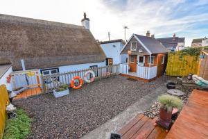 ein Hinterhof mit einem kleinen Haus und einer Holzterrasse in der Unterkunft Last-Minute Escapes l Sleeps Up to 4 l A delightful thatched cottage with all the modern facilities you will require l There are 2 bedrooms, one with a double bed l the other with two singles l Carrick Thatched Cottage l WeStayBelfast in Eden