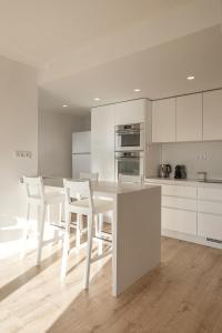 a white kitchen with a white table and chairs at Baleal Blue Sky in Ferrel