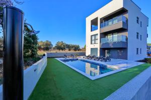 a house with a swimming pool in front of a building at Sunny Oasis in Bibinje
