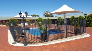 una recinzione con piante e un ombrellone accanto a una piscina di Gateway Motor Inn - Self Check-In a Broken Hill