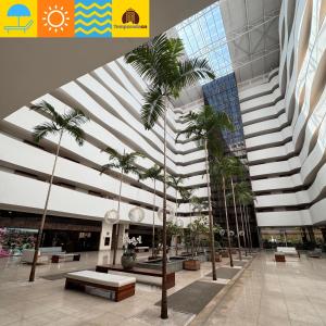 a large building with palm trees in a courtyard at Le Jardin - Temporada CN - Adriele in Caldas Novas