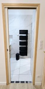 a bathroom with white marble walls and a black rack at Catel Studio hyper centre Saint Dizier in Saint-Dizier