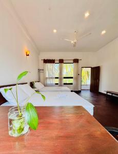 a bedroom with two beds and a table with a plant at Raa Pala Lake Resort in Anuradhapura