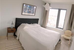 - une chambre avec un lit blanc, une chaise et une fenêtre dans l'établissement Spacious corner apartment with sea view, à Helsinki