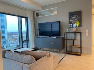 un salon avec un canapé et une télévision à écran plat dans l'établissement Spacious corner apartment with sea view, à Helsinki