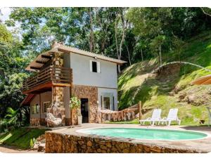 a house with a pool in front of it at Chalé Foroni in Cunha
