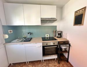 a small kitchen with white cabinets and a sink at ANNE - Maisonnette confortable avec Cour privée à Berck-Plage in Berck-sur-Mer