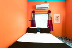 a bed in a room with an orange wall at Hotel O by OYO ALO Hotel in Phulbāri +23 photos