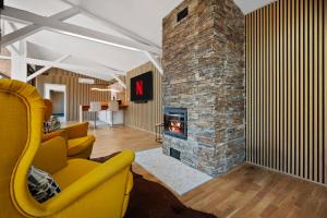 a living room with a fireplace and a yellow chair at Luxus-Gästehaus mit Sauna, Kamin & exklusivem Paarbereich in Neubulach