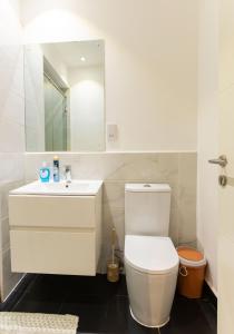 a white bathroom with a toilet and a sink at Central Studio Suite at Embassy Gardens in Accra
