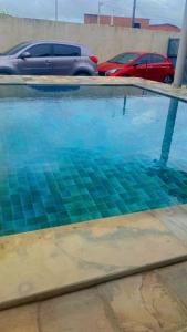 a pool of water with two cars in a parking lot at casa de praia em carne de vaca Pe in Carne de Vaca