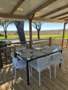 a table and chairs on a deck with a view of a field at Mobile Home 450 4-6 pers Camping Siblu Le Lac des Rêves in Lattes
