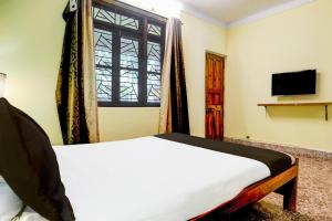 una camera da letto con un letto, una finestra e una televisione di Collection O Gauravaddo Calangute a Goa