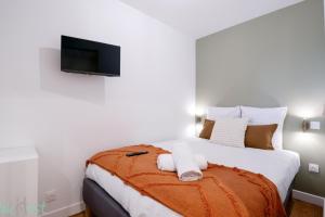 Un dormitorio con una cama con un televisor de pantalla plana en la pared. en Sublime 2-bedroom apartment - Historical center, en Burdeos