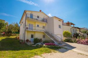 a large yellow house with stairs and flowers at Apartmani Tony in Banjole
