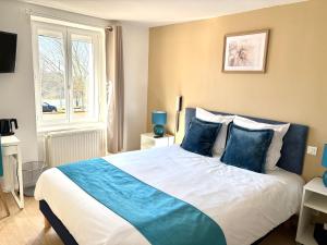 a bedroom with a large bed with blue pillows at Hôtel Comme chez soi in Jas