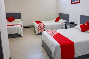 a room with three beds with red and white sheets at Hotel Puerta Sur in Comitán
