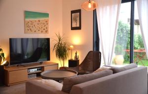 a living room with a couch and a tv at La vie est belle à 10 minutes de La Rochelle in Saint-Xandre