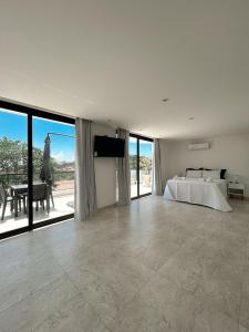 a white bedroom with a bed and a large window at La bardot boutique Pousada in Búzios