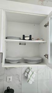 a white kitchen with white plates on shelves at Cozy One-Bedroom Apartment in Praia