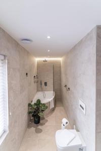 a bathroom with a tub and a toilet and a sink at The Charming Redwood Escape, New Forest in Ower