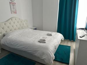 a bedroom with a white bed with blue rugs at AlyStar apartament in Mamaia Sat/Năvodari