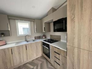 Una cocina con gabinetes de madera y un horno de estufa. en 41 Park Lane Patrington Haven 2 bedrooms sleeps 6 five stars park, en Patrington