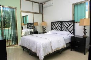 ein Schlafzimmer mit einem Bett mit weißen Laken und Fenstern in der Unterkunft Casa de Mario 4 Beautiful house with a huge pool in Cozumel + 26 Fotos