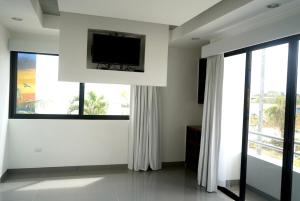 ein Wohnzimmer mit einem Flachbild-TV und 2 Fenstern in der Unterkunft Casa de Mario 4 Beautiful house with a huge pool in Cozumel