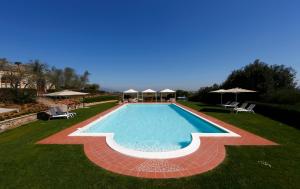 una piscina con sillas y sombrillas en un patio en Poggio al Casone en Crespina