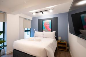 a bedroom with a white bed with a painting on the wall at Bohemian Barranco Apartments by Geko in Lima