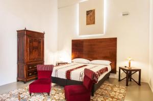 a bedroom with a bed and two red chairs at Casa Marsalia in Marsala