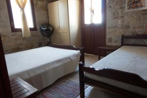 a bedroom with two beds and two windows at O Ilios House in Pitsidia