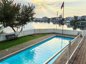 a swimming pool next to a river with a fence at Your Perfect Escape with Breathtaking Lake Views in Pretoria