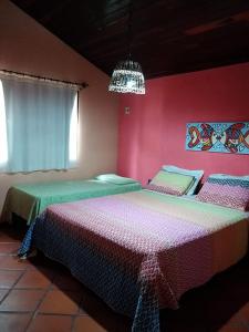 two beds in a room with pink walls at Pousada Aquarela Pipa in Pipa
