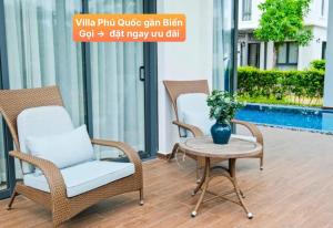 2 sillas y una mesa con un jarrón en el patio en Villa Phú Quốc Gần Biển, en Phu Quoc
