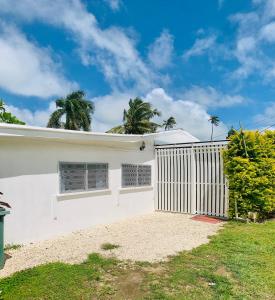 a white house with a fence and palm trees at Tonga Cottage - Entire Place with Aircon in Nuku‘alofa