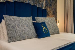 a bed with blue and gray pillows on it at Safira Suites 301 in Funchal