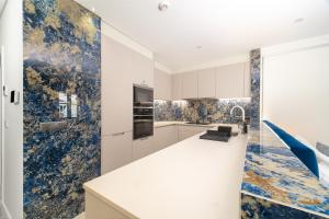a kitchen with white cabinets and blue wallpaper at Safira Suites 302 in Funchal