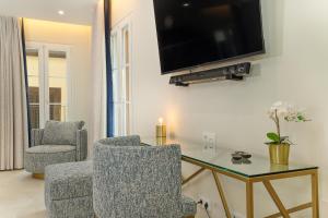 a living room with two chairs and a tv on a wall at Safira Suites 302 in Funchal
