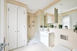 a white bathroom with a sink and a mirror at Spacious Fitzrovia Apartment 3 Bed in London