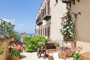 a balcony with a table and chairs and flowers at Torre Bennistra in Scopello